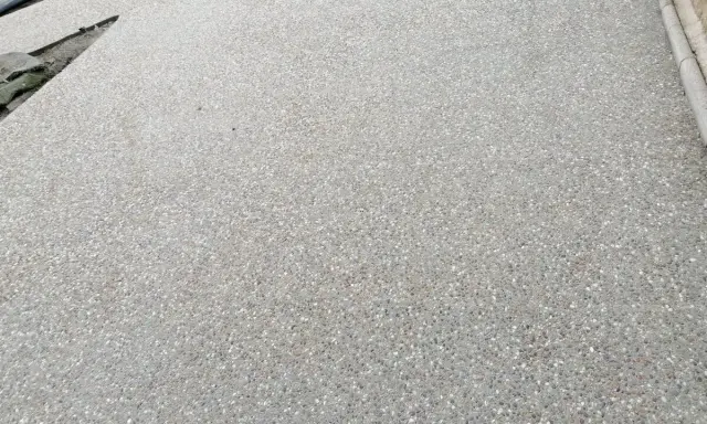 Superficie de hormigón desactivado con pequeñas piedras incrustadas, creando una textura rugosa y antideslizante.