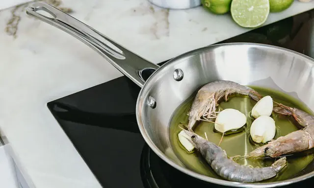 Camarones y ajo en sartén de acero inoxidable, un paso para como curar una sartén de acero inoxidable.