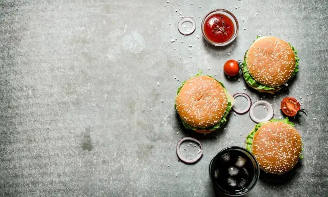 Tre saftiga hamburgare, en skål med ketchup, tomater, rödlök och en läsk med is. Perfekt för en mysig kväll på vår western grillhouse.