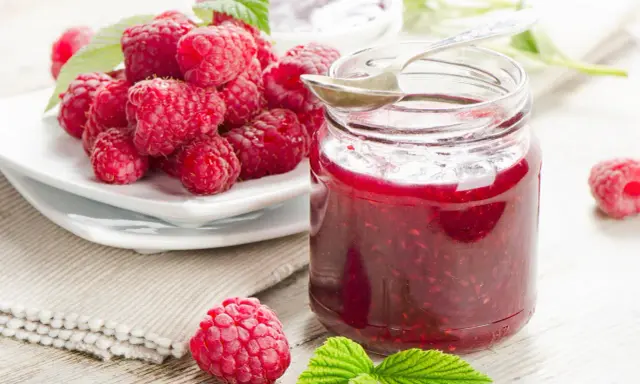 Frische Himbeeren und ein Glas selbstgemachte Himbeermarmelade. Ein einfaches Rezept für den Sommer.