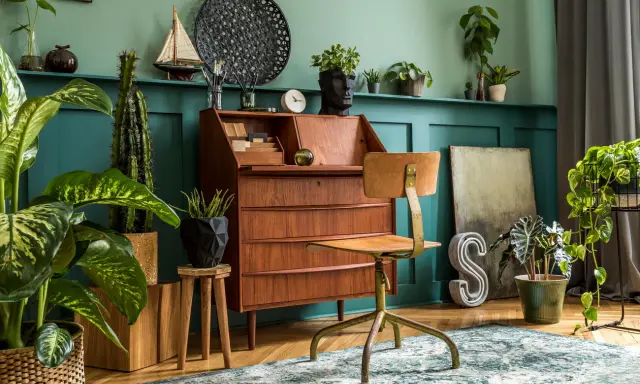 Wnętrze w stylu retro: drewniane biurko, krzesło, rośliny i dekoracje tworzą przytulną atmosferę.