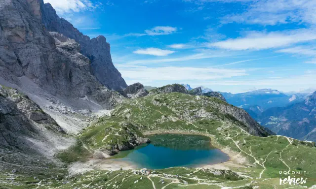 Lago di Coldai, incastonato tra le maestose vette delle Dolomiti, con sentieri che si snodano sui prati verdi.