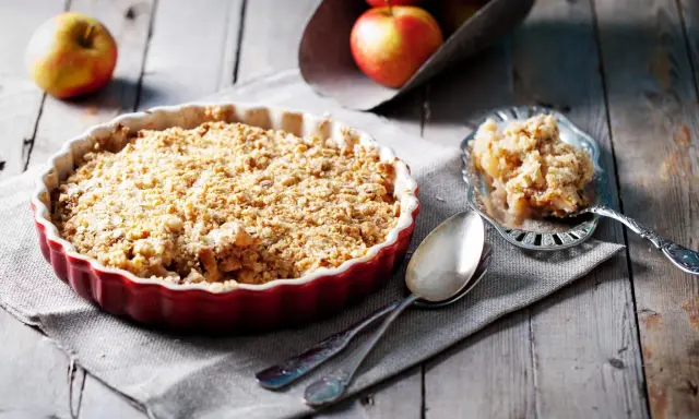 Un délicieux crumble aux pommes, avec sa pâte à crumble croustillante dorée, prêt à être dégusté.