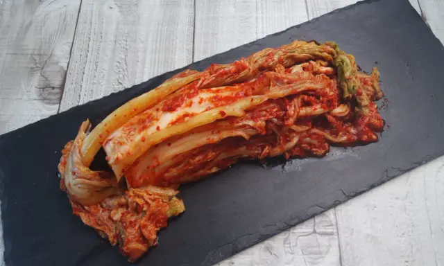 Frisch zubereitetes Kimchi, das beste Kimchi Rezept, liegt auf einem schwarzen Stein.