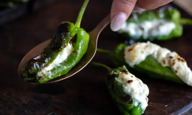 Grön paprika fylld med ost, som pimientos de padron, ligger på en sked.
