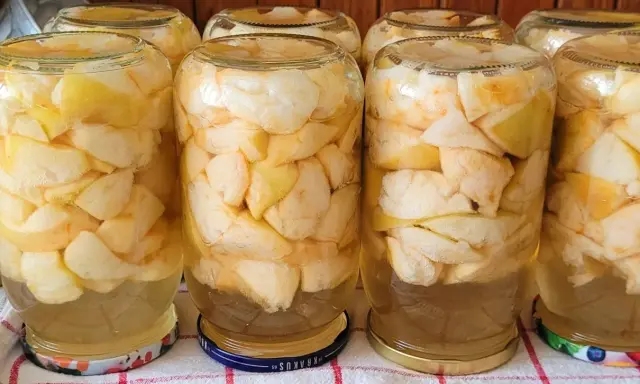 Słoiki wypełnione kawałkami jabłek, gotowe na pyszny kompot z jabłek.