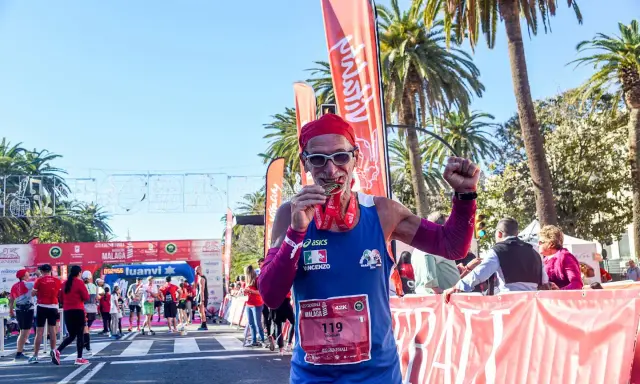 Lächelnder Läufer mit Medaille und rotem Kopftuch feiert seinen Erfolg beim Malaga Marathon.