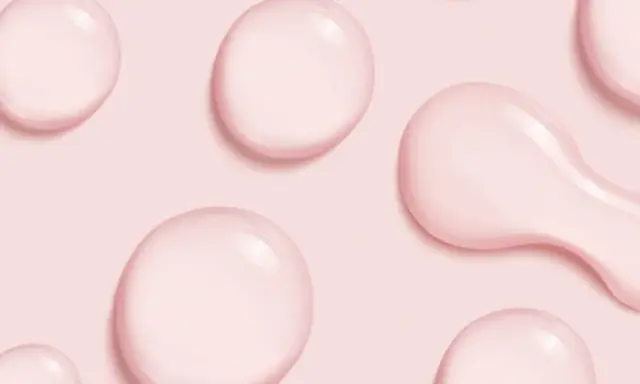 Gocce rosa su sfondo rosa, simili a quelle che si trovano in prodotti con cetearyl alcohol cos'è, un ingrediente emolliente.