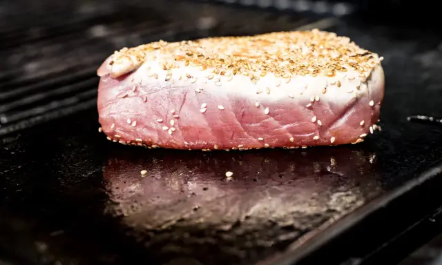 Surowy stek z tuńczyka w sezamie na rozgrzanym grillu.