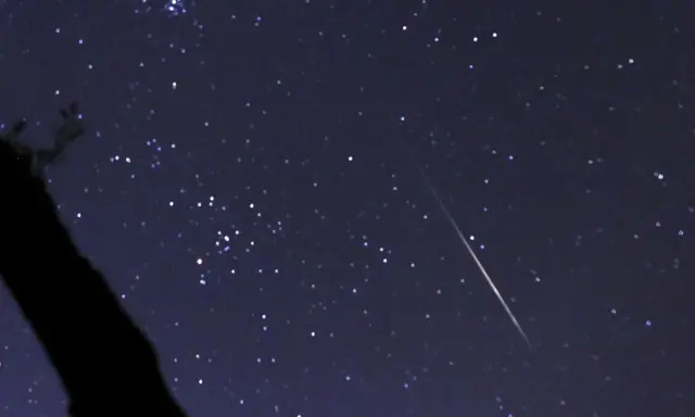 En stjärnklar natt med en meteor som drar en ljusstrimma över himlen, ett av många olika ljusfenomen på himlen.