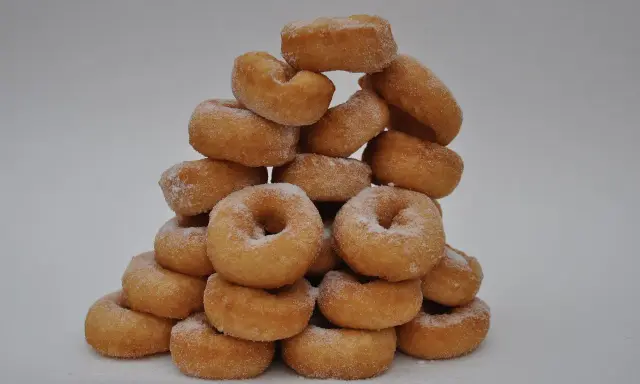 Pile de donuts dorés saupoudrés de sucre, parfaits pour une recette facile de donuts maison.