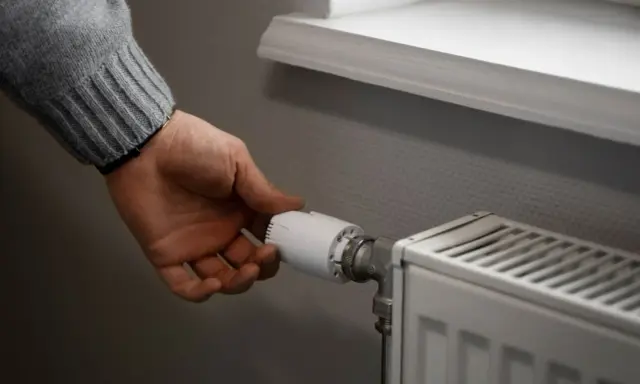 Dłoń reguluje termostat grzejnika. To przykład histerezy, czyli opóźnienia reakcji systemu na zmianę.