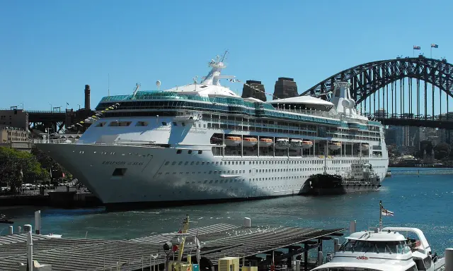 La Rhapsody of the Seas, un'imponente nave da crociera, attracca nel porto di Sydney, con l'iconico ponte sullo sfondo.