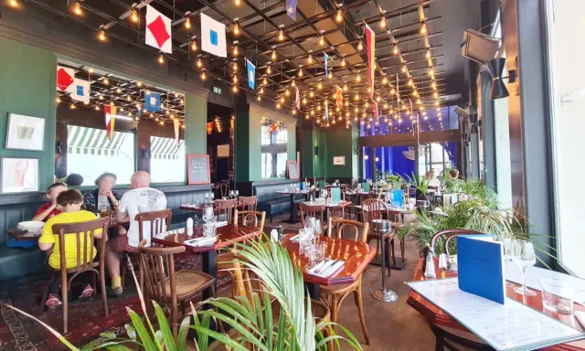 Ambiance marine dans un des restaurants de Saint-Malo. Drapeaux nautiques, lumières tamisées et tables dressées pour un repas convivial.