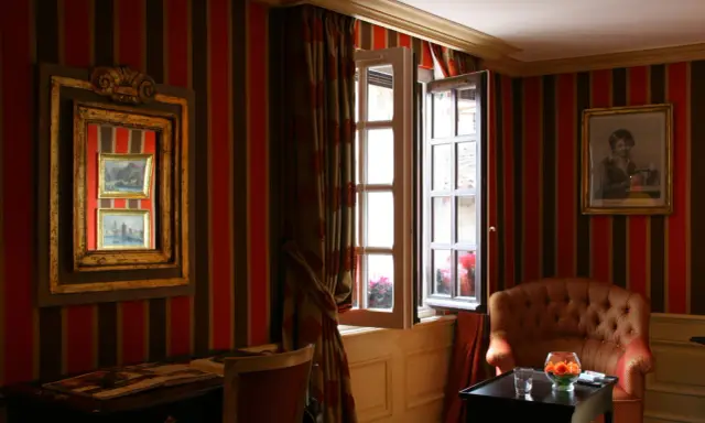 Fenêtre ouverte et miroir pour comment éclaircir une pièce sombre. Un fauteuil confortable et un bureau complètent ce décor.