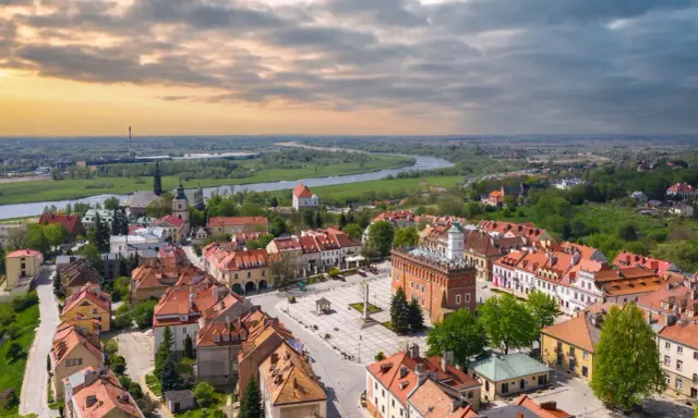 Urokliwy rynek i rzeka w miasto zakochanych w Polsce. Dachy kamienic i zieleń tworzą malowniczy krajobraz.