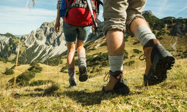 Dobre buty w góry latem to podstawa. Para wędrowców w solidnych trekkingowych butach i skarpetach pokonuje górski szlak.