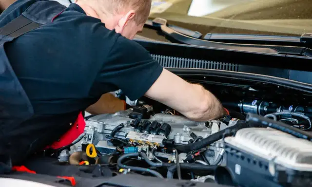 Mechanik pracuje przy silniku z instalacją gazową. Sprawdza podzespoły, by zapewnić optymalną cng cenę za litr.