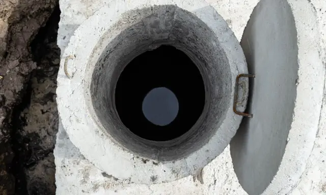 Otwarty betonowy właz szamba, widok z góry. Rozważasz, jak uszczelnić szambo betonowe od środka?