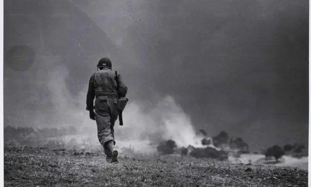 Soldato solitario cammina verso il fumo di battaglia, un'iconica immagine di Robert Capa.