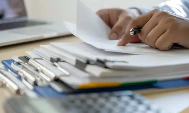 Ręce przeglądają dokumenty, szukając informacji, kiedy można wymeldować członka rodziny.