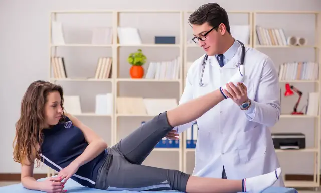 Fizjoterapeuta bada nogę pacjentki. Dowiedz się, jak zostać fizjoterapeutą i pomagać w powrocie do zdrowia.