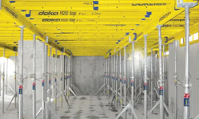 Sistema de apeo estructural Doka H20 top, con puntales metálicos y vigas amarillas, listo para soportar una losa.
