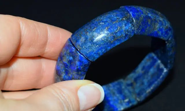 Błękitna bransoleta z lapis lazuli, z widocznymi złotymi inkluzjami pirytu, prezentowana na dłoni.