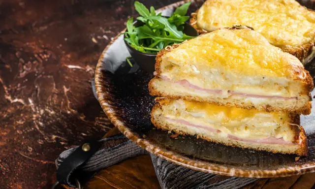 Deux croque monsieur bechamel dorés, garnis de jambon et de fromage fondant, servis avec une salade verte.