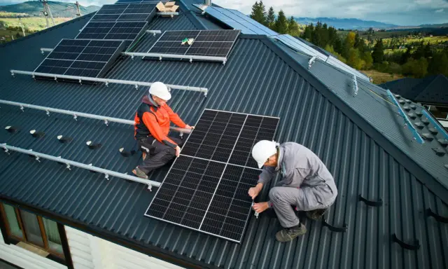 Zwei Monteure installieren Solarmodule auf einem Dach. Die Frage "was kostet eine PV Anlage mit Speicher" beschäftigt viele Hausbesitzer.