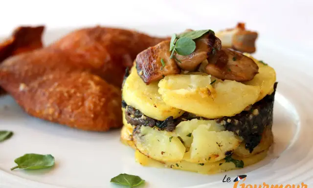 Plat de pommes de terre en millefeuille avec du foie gras et des champignons, accompagné de volaille rôtie.