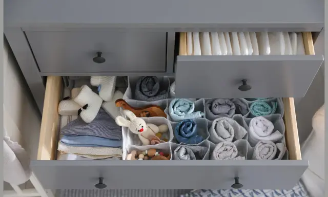 Ordentliche Schubladen einer Wickelkommode beschriften: Windeln oben, Babykleidung und Spielzeug unten, alles übersichtlich sortiert.