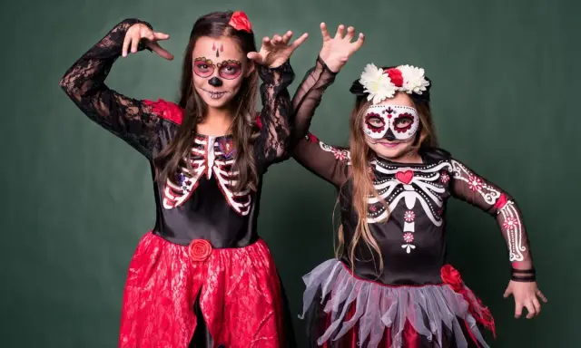Dwie dziewczynki w strojach szkieletów z makijażem na Dzień Zmarłych. Inspiracja, jak się przebrać na Halloween.