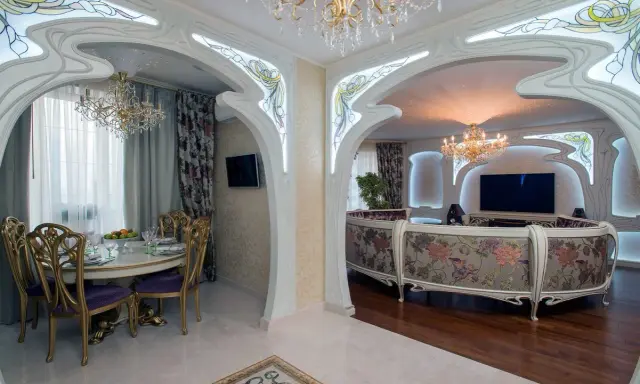 Ett lyxigt vardagsrum och matsal i art nouveau jugendstil med blommig soffa, kristallkronor och utsmyckade valv.