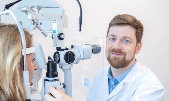 Okulista przeprowadza test na nadwzroczność u pacjentki, badając jej wzrok za pomocą specjalistycznego sprzętu.
