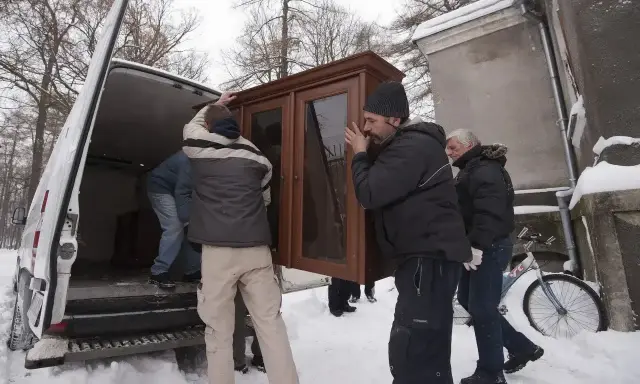 Mężczyźni wynoszą mebel z domu, by uniknąć eksmisji. Zimowa aura i śnieg nie powstrzymują przeprowadzki.