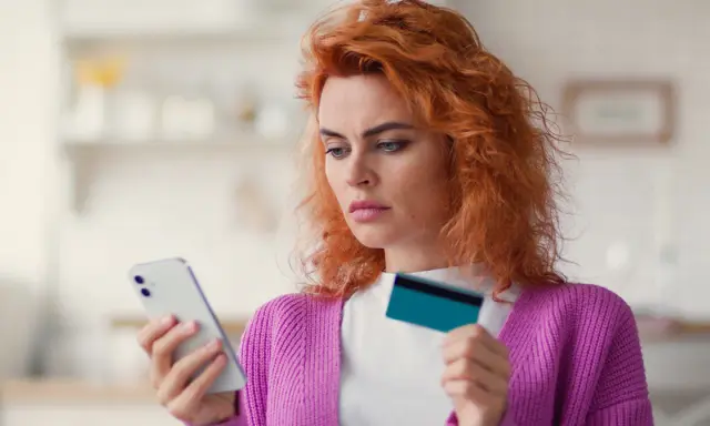 Zastanawia się, co to jest dip, przeglądając ofertę w telefonie z kartą w dłoni.