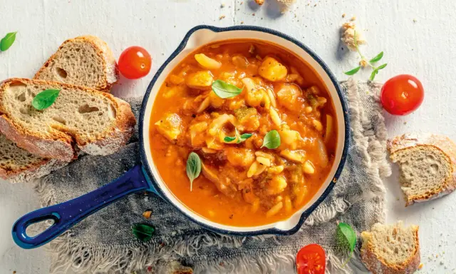 Herzhafte italienische Suppe mit Gemüse und Nudeln, serviert mit rustikalem Brot und frischen Tomaten. Ein Genuss für kalte Tage.