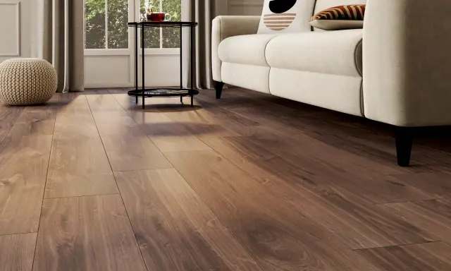 Un salon lumineux avec un nouveau revêtement sol en bois chaleureux, un canapé crème et des coussins décoratifs.