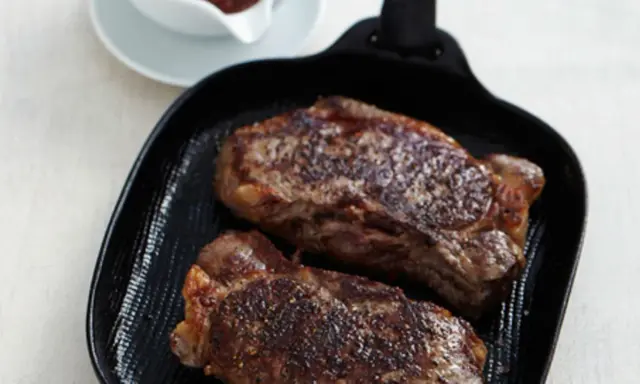 Zwei saftige Rumpsteaks braten in einer Grillpfanne, perfekt gewürzt und bereit zum Genuss.