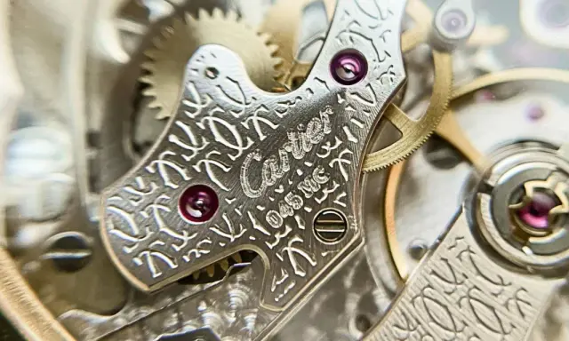 Dettaglio del movimento di un orologio Cartier, con incisioni guilloché e rubini. La joux perret, un capolavoro di precisione.