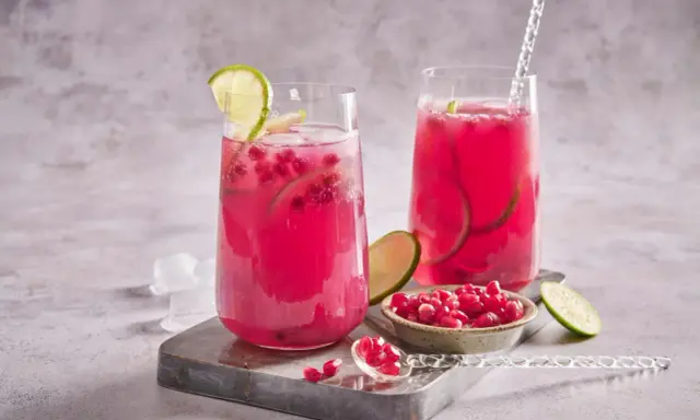 Cocktail fruité et rafraîchissant, ce cocktail fruit du dragon est garni de quartiers de citron vert et de graines de grenade.