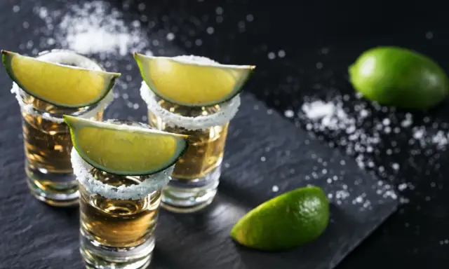 Kieliszki tequili z solą i limonką. Idealne dodatki, by wiedzieć, z czym pić tequilę.