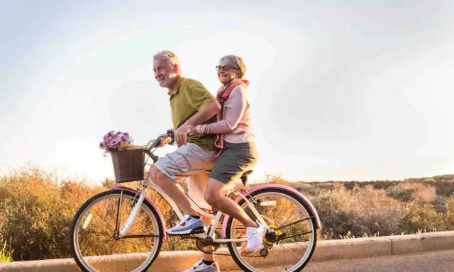 Pareja mayor disfruta de un paseo en bicicleta, celebrando la jubilación a los 61 años con la nueva reforma.