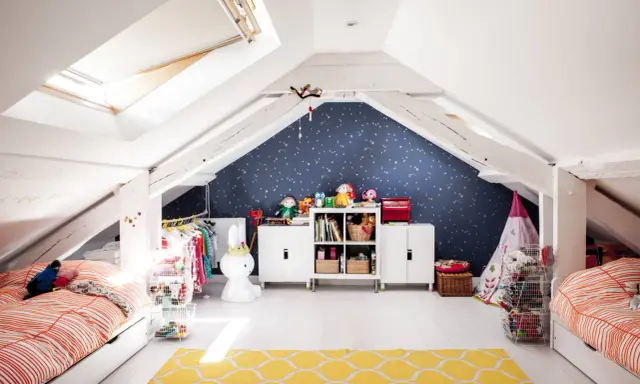 Kreative kinderzimmer dachboden ideen: zwei Betten, Spielzeug, Kleiderständer und ein Sternenhimmel an der Wand schaffen eine gemütliche Atmosphäre.