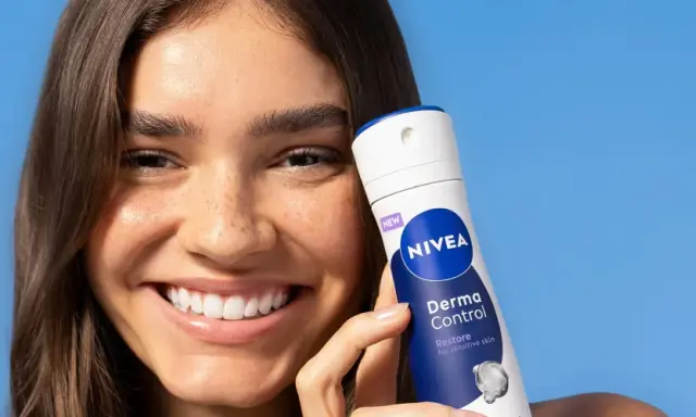 Donna sorridente con prodotto Nivea Derma Control, ideale per chi soffre di bruciore sotto le ascelle.