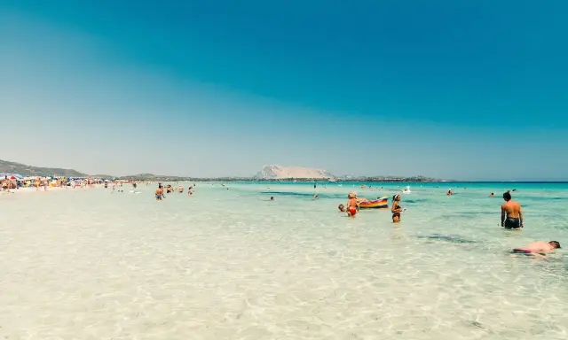 Acque cristalline e gente felice in spiaggia, forse qual è la parte più bella della Sardegna? Un paradiso azzurro.