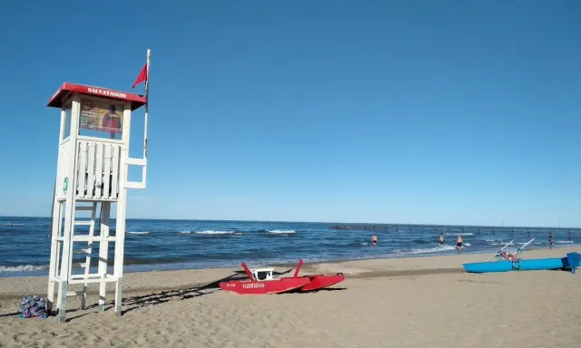 Torre di salvataggio e barchini sulla spiaggia di Rimini, pronti per nuove storie di mare.