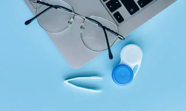 Okulary, pojemnik na soczewki i pęseta leżą obok laptopa. Czy można nosić soczewki i okulary jednocześnie?