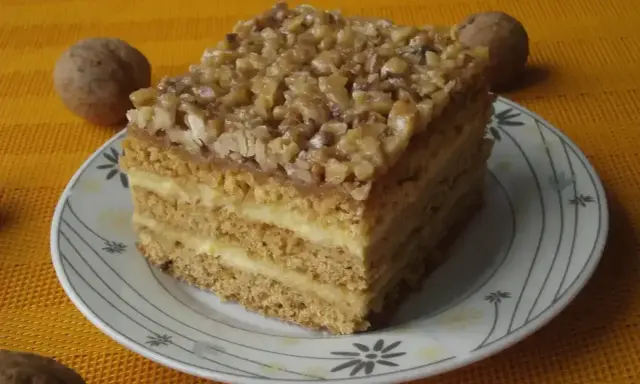 Pyszne ciasto miodowe z orzechami, jedno z 10 najlepszych ciast, na talerzyku z orzechami w tle.